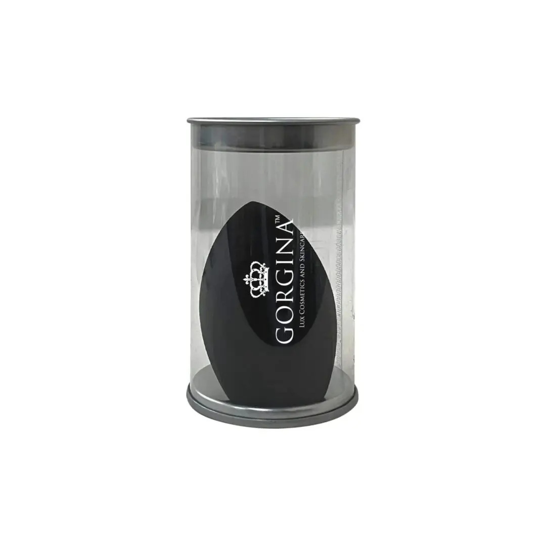 A black makeup sponge in a clear cylindrical plastic container with a gray base and lid.