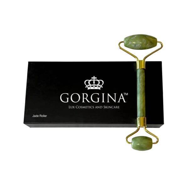 Green jade facial roller laying on a black box with "Gorgina Lux Cosmetics and Skincare" written on it.