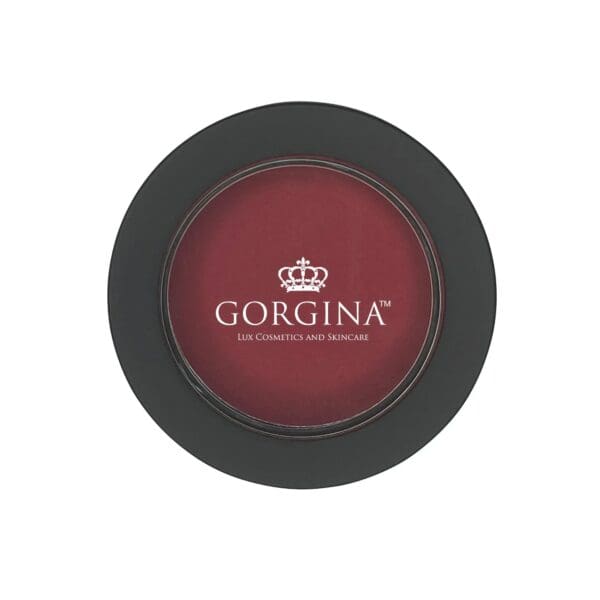 Circular container of Gorgina blush with dark red color and black lid, featuring a crown logo and text "Gorgina Lux Cosmetics and Skincare.