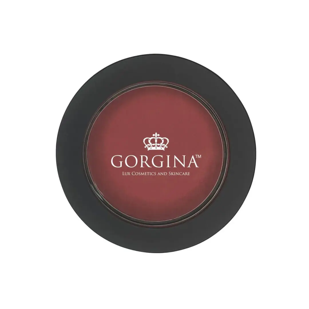 A round, black container of Gorgina Lux Cosmetics and Skincare blush with a maroon shade and a crown logo on the lid.