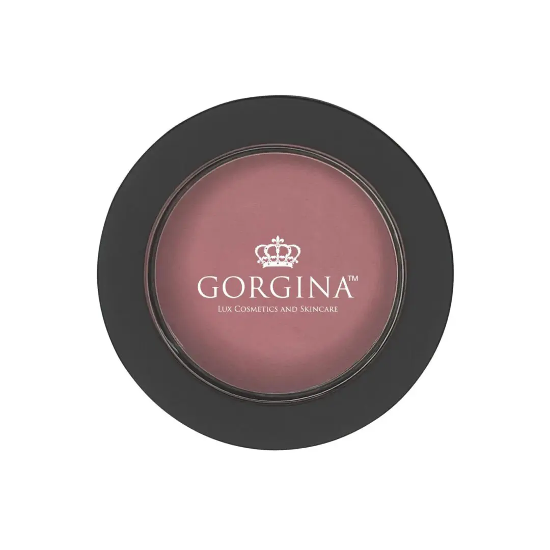 A round container of Gorgina Lux Cosmetics and Skincare blush with a black lid and transparent top showing the pink blush inside.