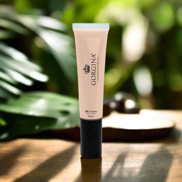 A tube of Gorgina BB Cream is placed upright on a wooden surface with green leaves blurred in the background.