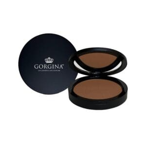 A round black compact labeled "Gorgina" opens to reveal a brown pressed powder makeup product, with the lid placed beside it.