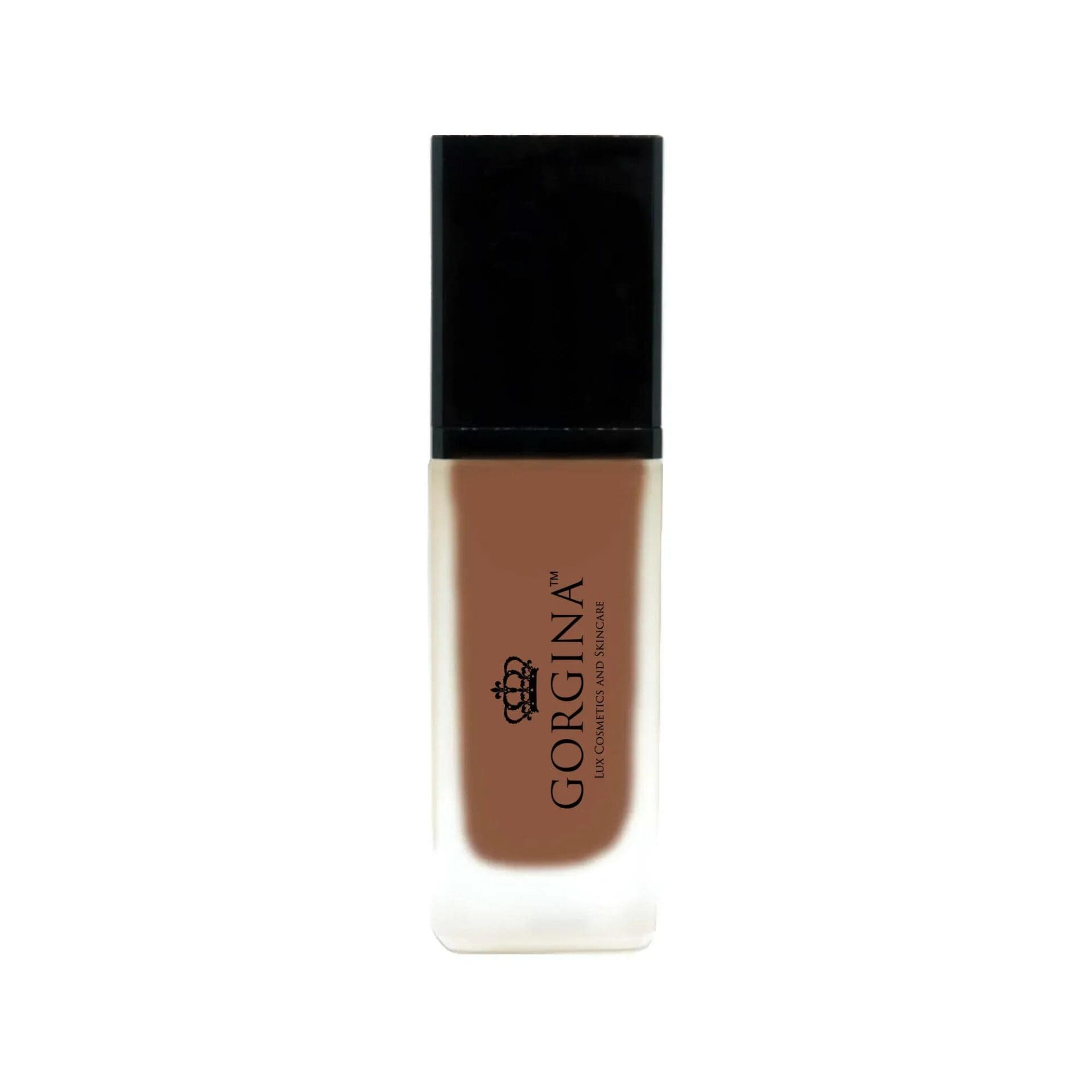 A bottle of Gorgina liquid foundation with a black cap and frosted glass bottle containing medium brown makeup.