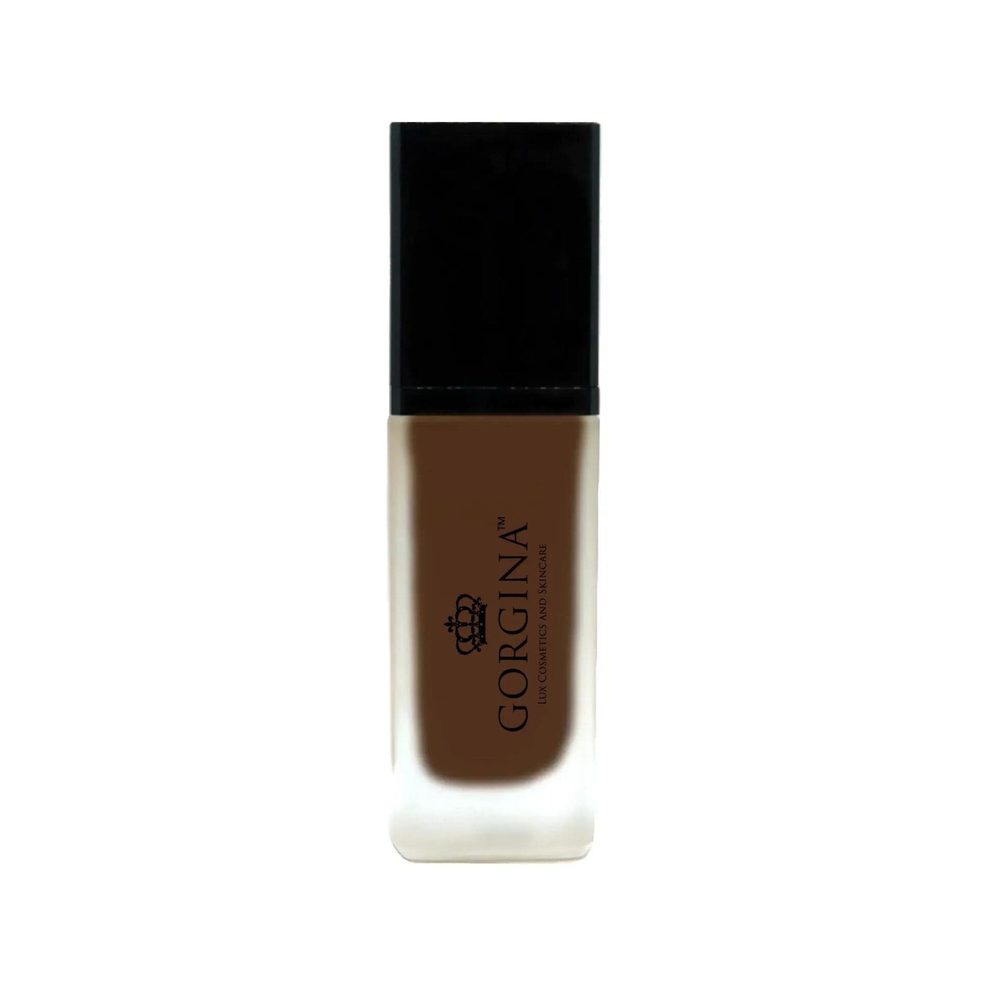 A bottle of Gorgina liquid foundation with a black cap and frosted glass body, containing dark brown makeup.