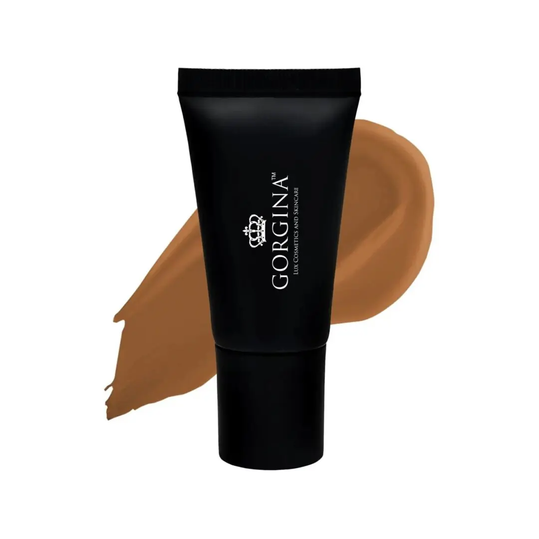 A black tube labeled "Gorgina" stands in front of a brown smear of makeup, indicating the shade of the cosmetic product.
