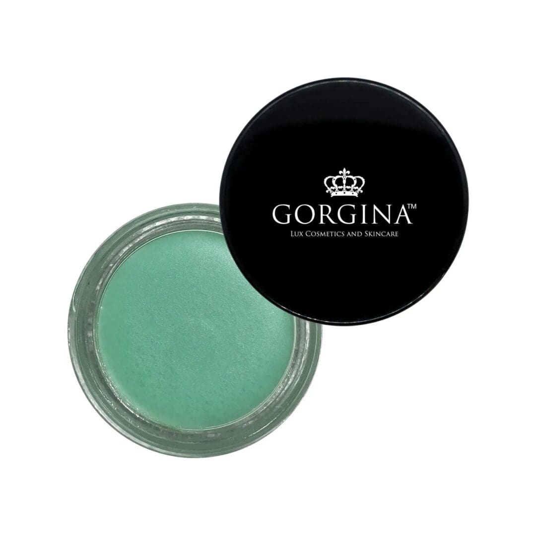 An open container of green cream or balm with a black lid labeled "Gorgina Lux Cosmetics and Skincare.